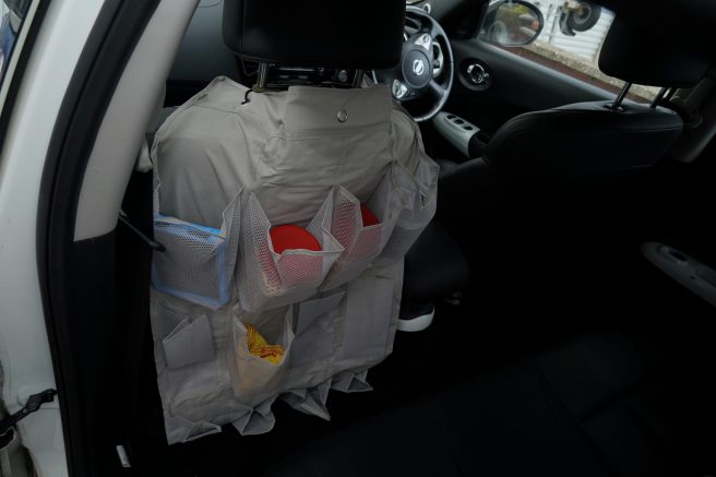 An image of a door shoe hanger on the back of a car seat to provide storage.